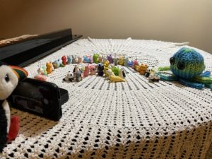 A stuffed puffin taking a picture of a stuffed octopus and animal erasers.