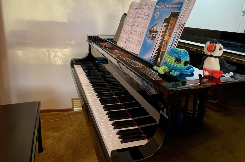 A piano with music books and two small stuffed animals